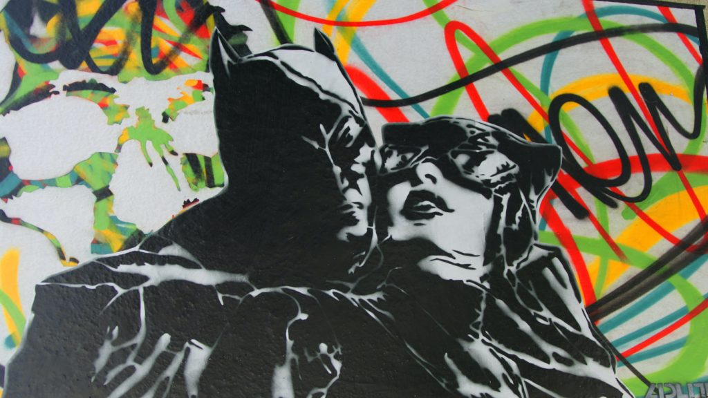 Batman has caught catwoman from behind, black and white with colored background courtesy of Pascal Bernardon