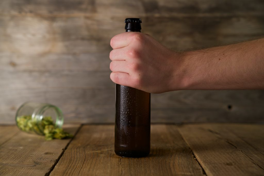 Male hand fist sets down mead bottle on wooden table top