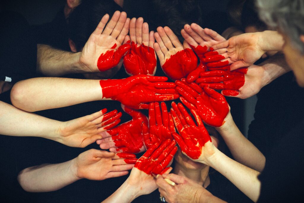 People group hands together and paint on them to create a large red heart