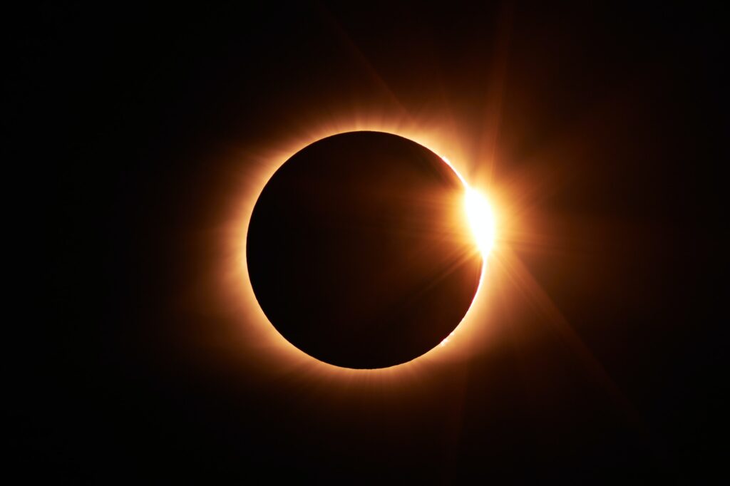 solar eclipse creates a red ring with a small flare that makes it look like a gold ring with a diamond