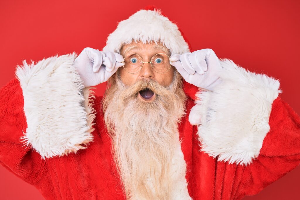 Santa with a surprised expression holds his round glasses to his eyes