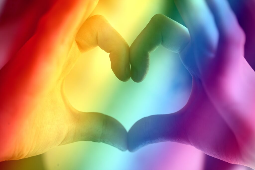 Hand make the shape of a heart with rainbow colored overlay
